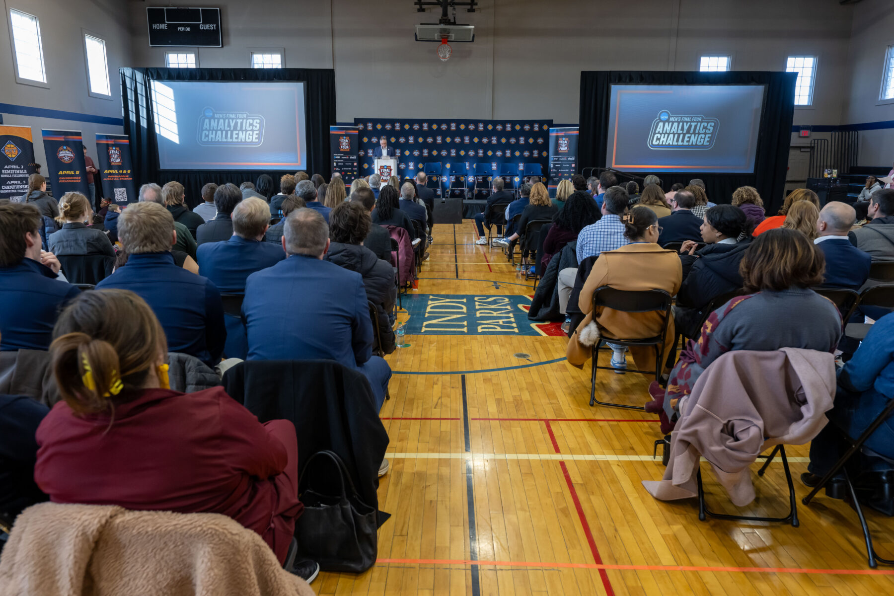 Audience seated with speaker on stage at a Men's Final Four podium