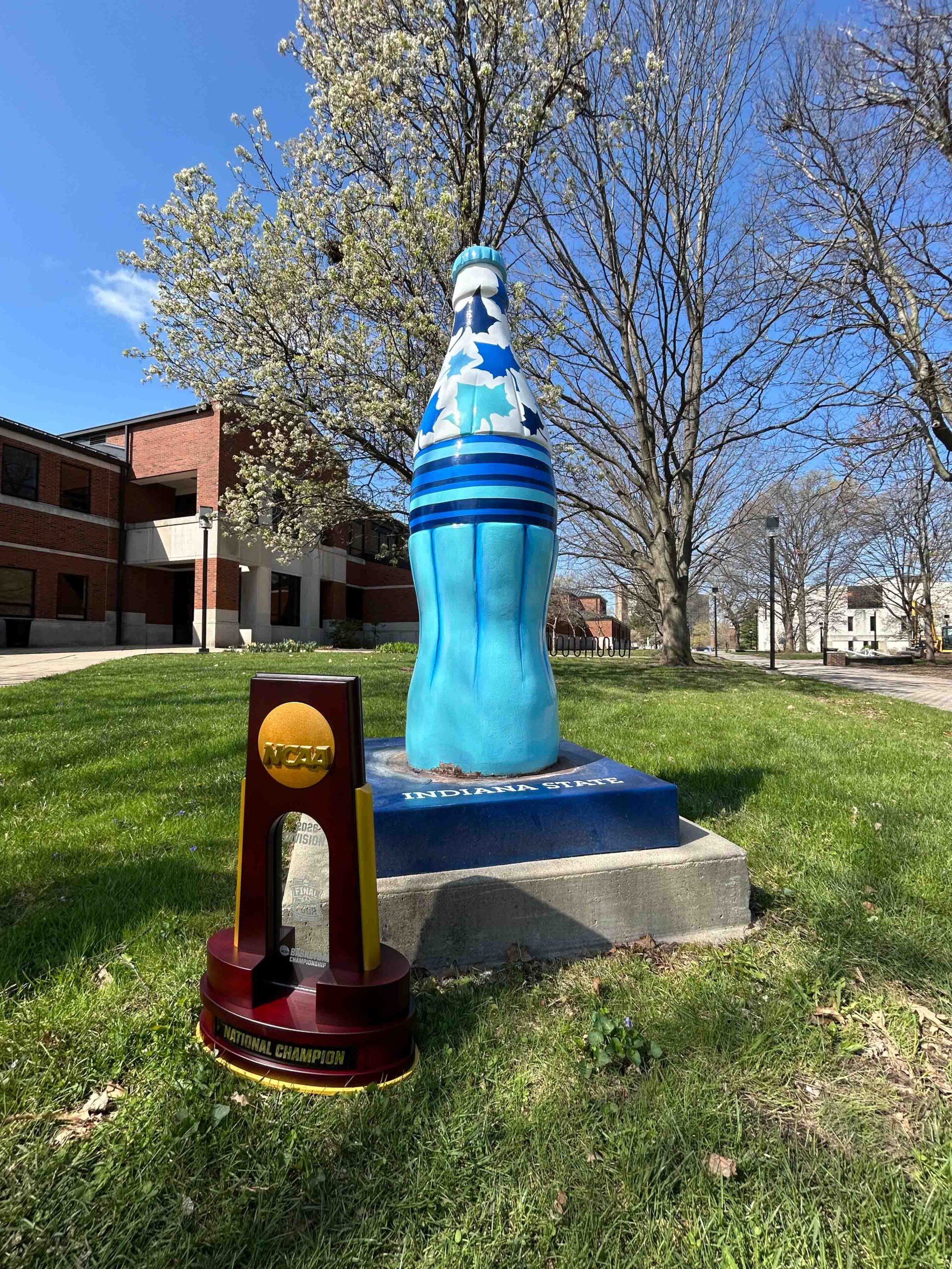 The 2026 NCAA Men's Final Four trophy in front of a Coca-Cola statue at Indiana State University.