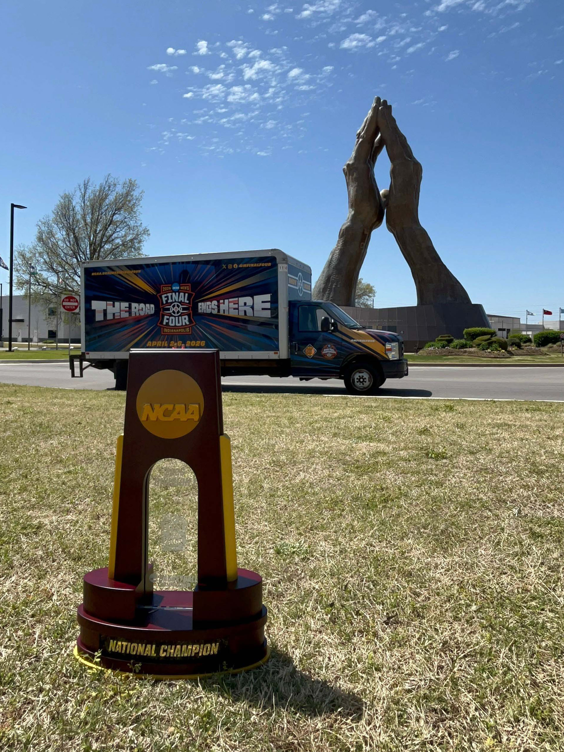 The 2026 NCAA Men's Final Four trophy in front of the Praying Hands sculpture at Oral Roberts University.